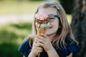 an excited kid in glasses holding an ice cream cone with two scoops