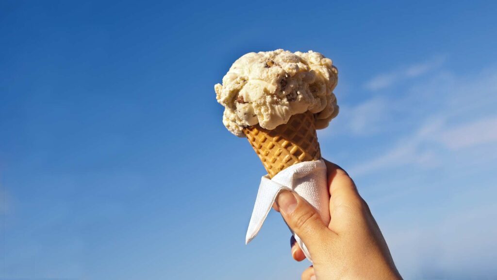 a person holding an ice cream cone on a sunny day